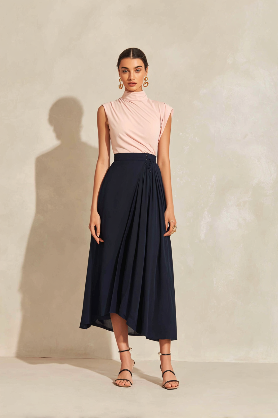 A model wearing a fitted elegant top in blush pink paired with a flowing A-line midi skirt in navy, accented by gold hoop earrings and strappy sandals, standing confidently against a neutral backdrop with soft light, representing a stylish and memorable graduation outfit --ar 2:3 --v 7 --style raw